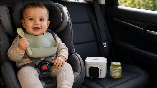 Bebe sentado en silla en el coche con su calentador de potitos de Popetes al lado, esperando para comer
